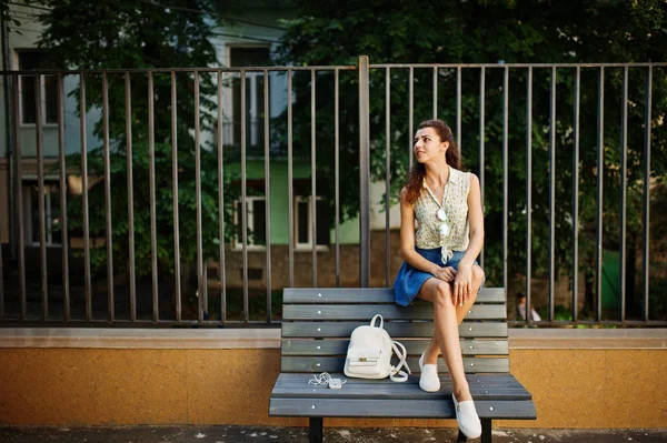 Curly elegante menina desgaste na saia jeans azul, blusa sentado em b — Fotografia de Stock
