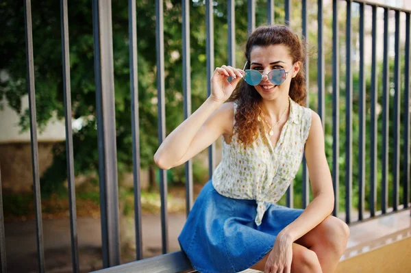 Vestido de niña con estilo rizado en falda vaqueros azules, blusa sentado en b —  Fotos de Stock