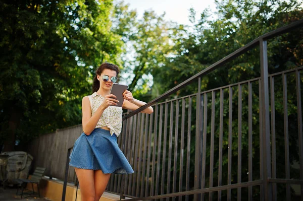 Curly elegante menina desgaste na saia jeans azul, blusa com tablet — Fotografia de Stock