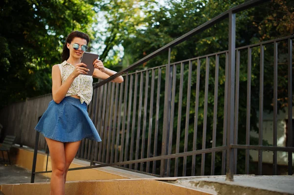 Curly elegante menina desgaste na saia jeans azul, blusa com tablet — Fotografia de Stock