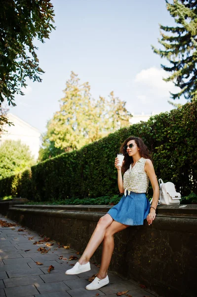 Krullend stijlvolle meisje slijtage van blue jeans rok, blouse en glazen — Stockfoto