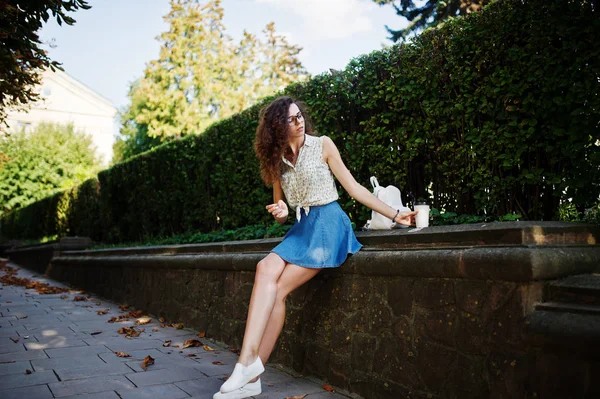 Curly elegante menina desgaste na saia jeans azul, blusa e óculos — Fotografia de Stock