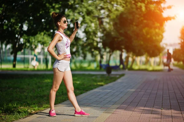 Desporto menina desgaste em shorts brancos e camisa fazendo selfie no parque . — Fotografia de Stock