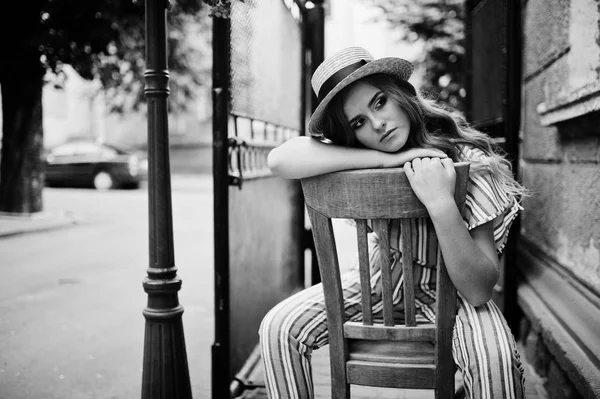 Portrait of a fabulous young woman in striped overall and hat si — Stock Photo, Image