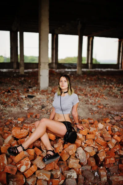 Girl wear on shorts at abadoned factoty sitting on brick. — Stock Photo, Image