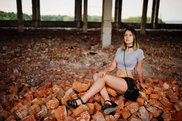 Girl wear on shorts at abadoned factoty sitting on brick. — Stock Photo, Image