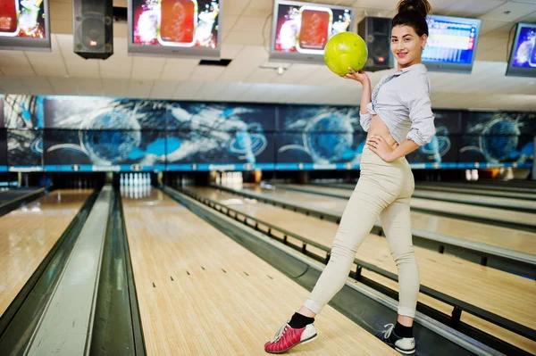 Girl with bowling ball on alley played at bowling club.