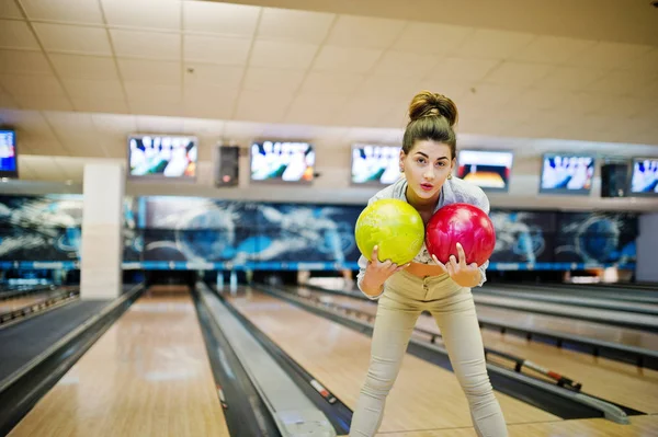 Girl with bowling ball on alley played at bowling club.