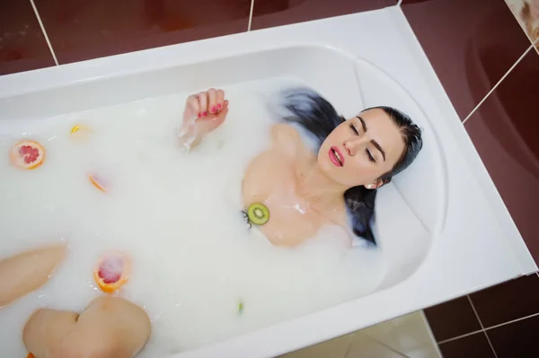 Сексуальная брюнетка в ванной с молоком и фруктами. Молодежь b — стоковое фото