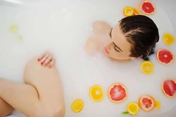 Сексуальная брюнетка в ванной с молоком и фруктами. Молодежь b — стоковое фото