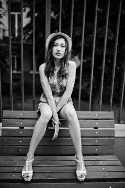 Şaşırtıcı uzun bacaklı kız giymek benc poz şapka hig topuklu