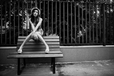 Şaşırtıcı uzun bacaklı kız giymek benc poz şapka hig topuklu