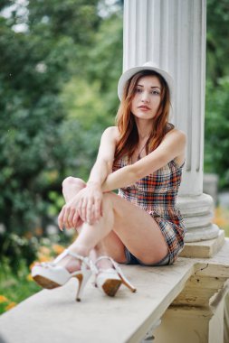 Hig topuklu kız ile şaşırtıcı uzun bacaklı v oturan şapka giymek