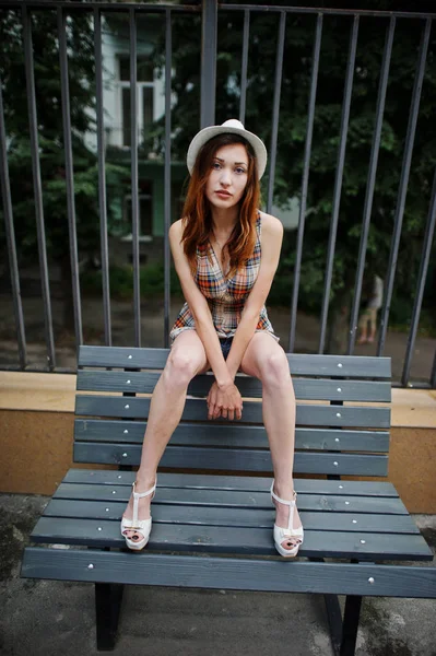 Şaşırtıcı uzun bacaklı kız giymek benc poz şapka hig topuklu