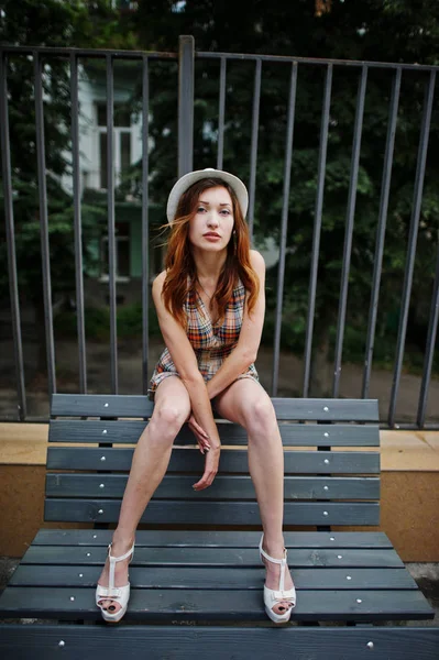 Şaşırtıcı uzun bacaklı kız giymek benc poz şapka hig topuklu