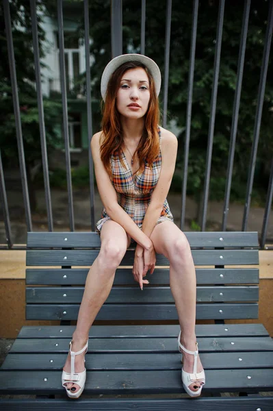 Şaşırtıcı uzun bacaklı kız giymek benc poz şapka hig topuklu