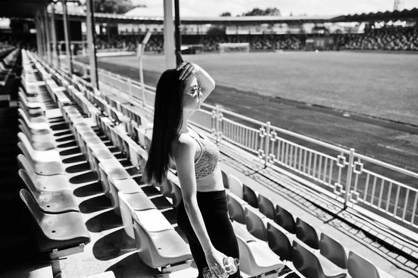 Спортивная девушка в спортивной одежде и солнцезащитных очках позирует на стадионе — стоковое фото