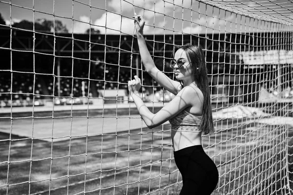 Спортивная девушка в спортивной одежде и солнцезащитных очках позирует на стадионе — стоковое фото