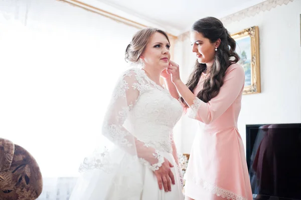 彼女の結婚式のイヤリングをつけるには、花嫁を助ける美しい花嫁介添人 — ストック写真