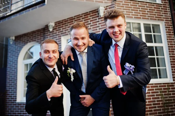 Knappe bruidegom in zijn bruiloft tuxedo poseren met groomsmen of worden — Stockfoto