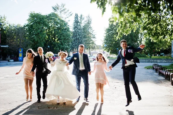 Casal de casamento feliz e noivos com padrinhos correndo e j — Fotografia de Stock