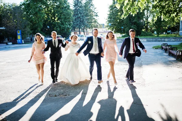 Feliz boda pareja y bridesmids con los padrinos corriendo y j — Foto de Stock