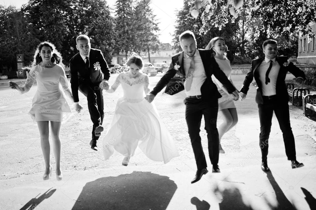 Happy wedding couple and bridesmids with groomsmen running and j
