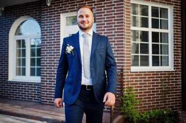 Yakışıklı bir genç damat bir tuğla ev ile poz portresi 