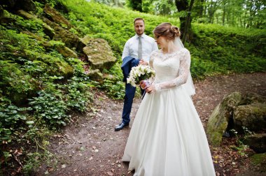 Ormanın içinde arka planda büyük kayalar ile poz yeni evliler