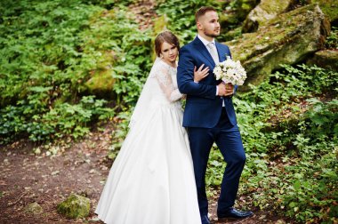 Ormanın içinde arka planda büyük kayalar ile poz yeni evliler