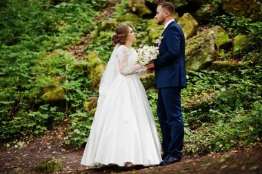 Ormanın içinde arka planda büyük kayalar ile poz yeni evliler