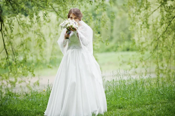 Portret van een mooie jonge bruid poseren met een boeket outdoo — Stockfoto