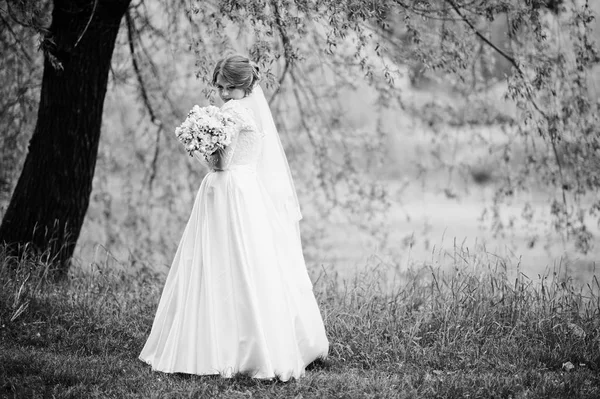 Retrato de una hermosa joven novia posando con un ramo de outdoo —  Fotos de Stock