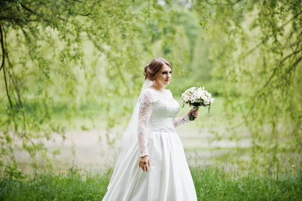 Portrait of a beautiful young bride posing with a bouquet outdoo — Stock Photo, Image