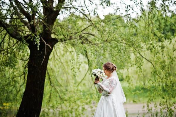 Retrato de una hermosa joven novia posando con un ramo de outdoo — Foto de Stock