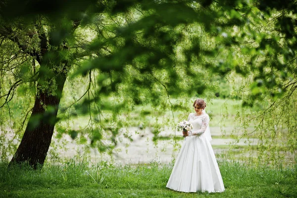 Portréja egy gyönyörű fiatal menyasszony pózol egy csokor outdoo — Stock Fotó