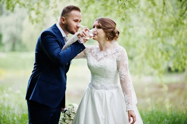 Coppia di sposi che beve champagne nella foresta o par — Foto Stock