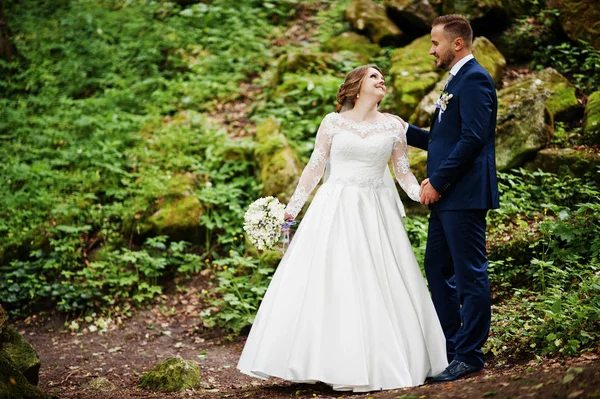 Ormanın içinde arka planda büyük kayalar ile poz yeni evliler