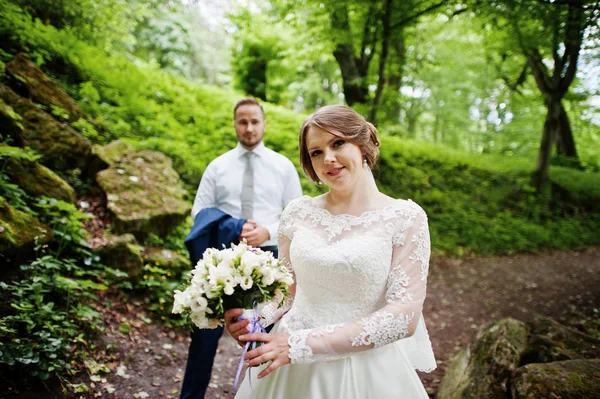 Recém-casados posando com enormes pedras no fundo da floresta — Fotografia de Stock