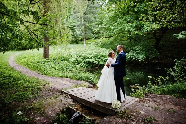 Casal de casamento atraente de pé e posando em uma pequena madeira — Fotografia de Stock