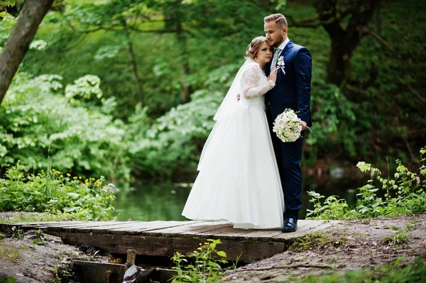 Casal de casamento atraente de pé e posando em uma pequena madeira — Fotografia de Stock