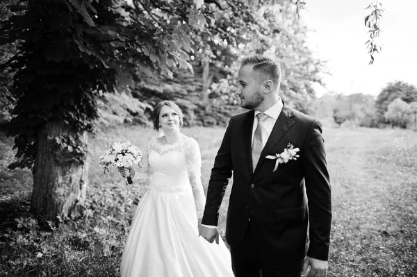Casal de casamento incrível andando e posando em algum lugar no verde — Fotografia de Stock