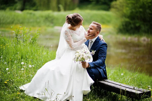 Fantastische bruid zittend op een bruidegom schoot in de weide naast t — Stockfoto