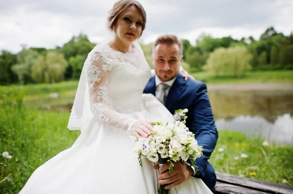 Fantastický nevěsta sedí na klíně ženicha na louce vedle t — Stock fotografie