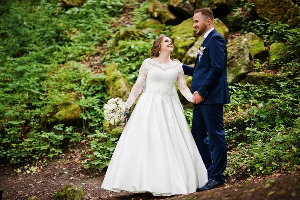Ormanın içinde arka planda büyük kayalar ile poz yeni evliler