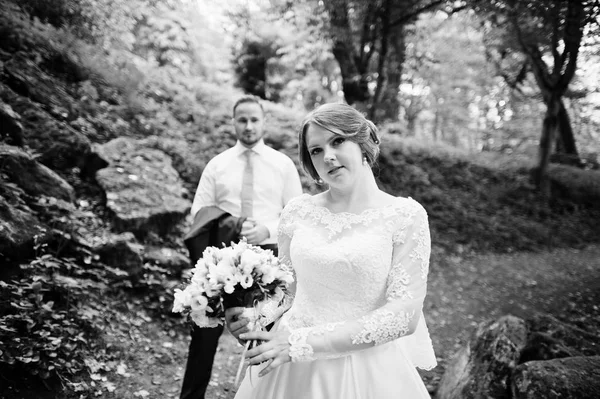 Recém-casados posando com enormes pedras no fundo da floresta — Fotografia de Stock