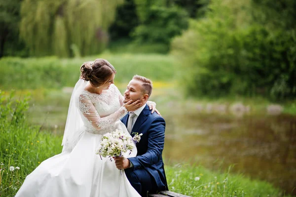 Fantastische bruid zittend op een bruidegom schoot in de weide naast t — Stockfoto