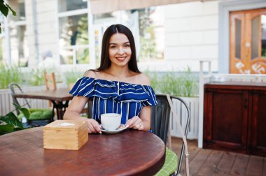 Fincan ile kafede masada oturan güzel esmer kız 