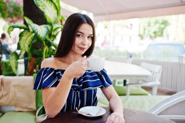 Fincan ile kafede masada oturan güzel esmer kız 