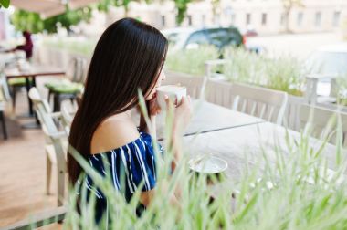 Fincan ile kafede masada oturan güzel esmer kız 